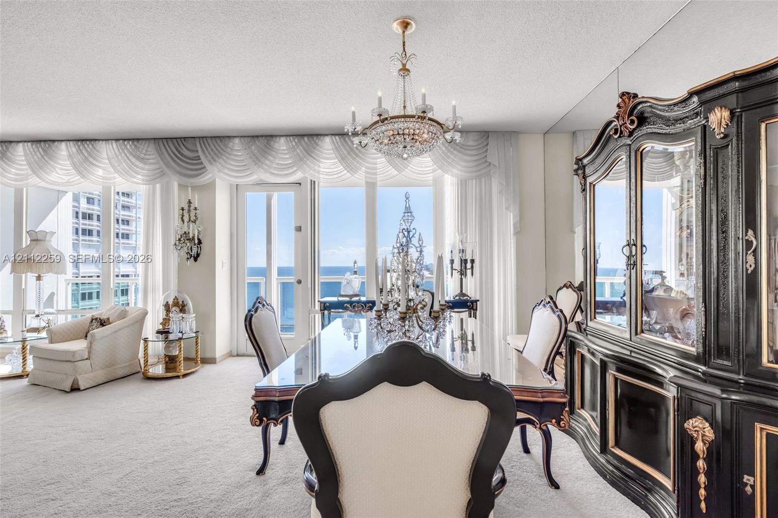 Floor-to-ceiling windows, crystal chandelier, mirrored wall paneling, and a glass-paneled door