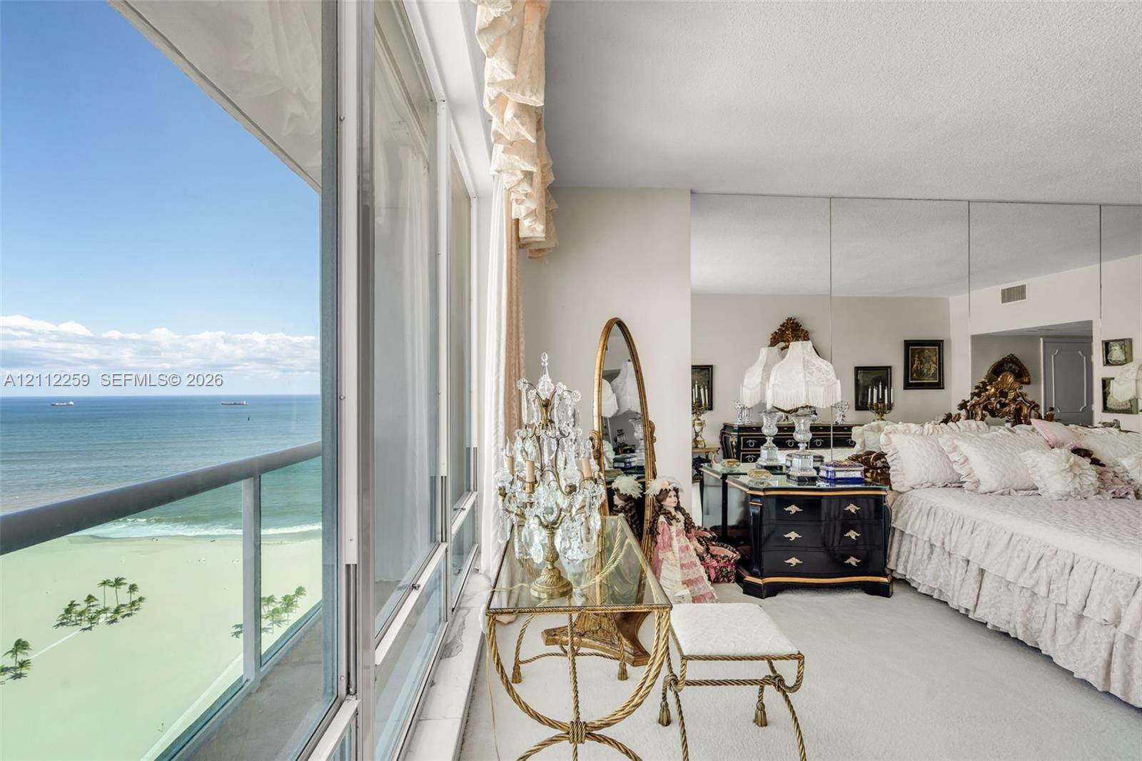 Floor-to-ceiling windows, sliding glass door with balcony access, full-wall mirror, and wall-to-wall carpeting