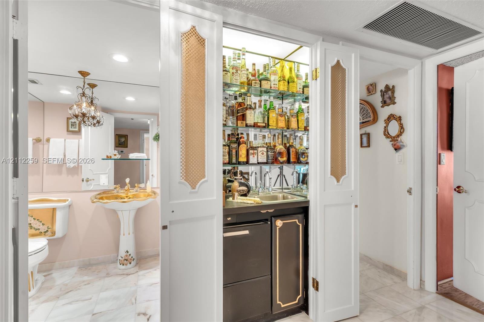 Built-in wet bar featuring glass shelving, mirrored backsplash, and under-counter cabinetry