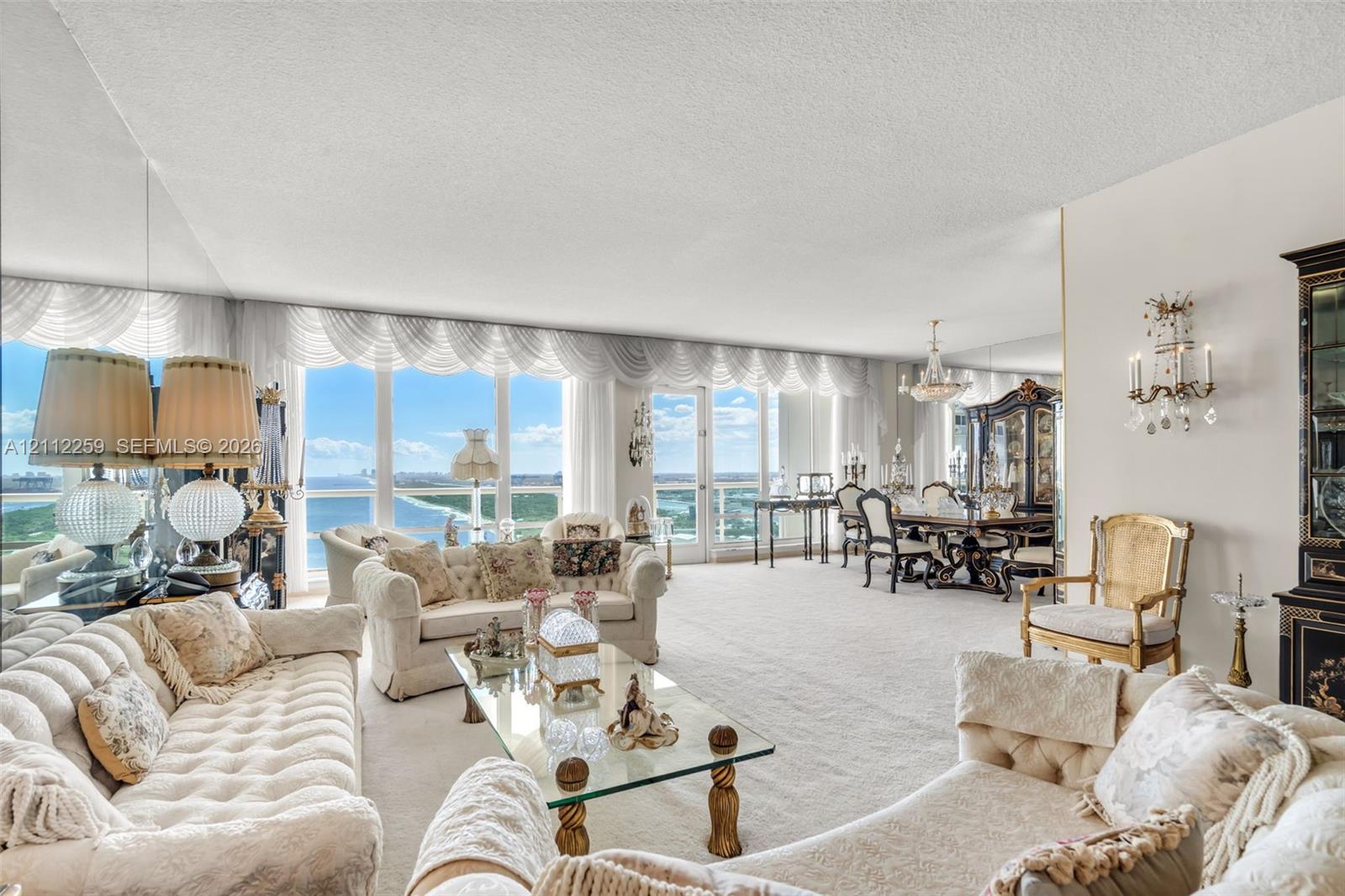 Floor-to-ceiling windows, mirrored wall accents, wall-mounted decorative sconces, and neutral carpeting