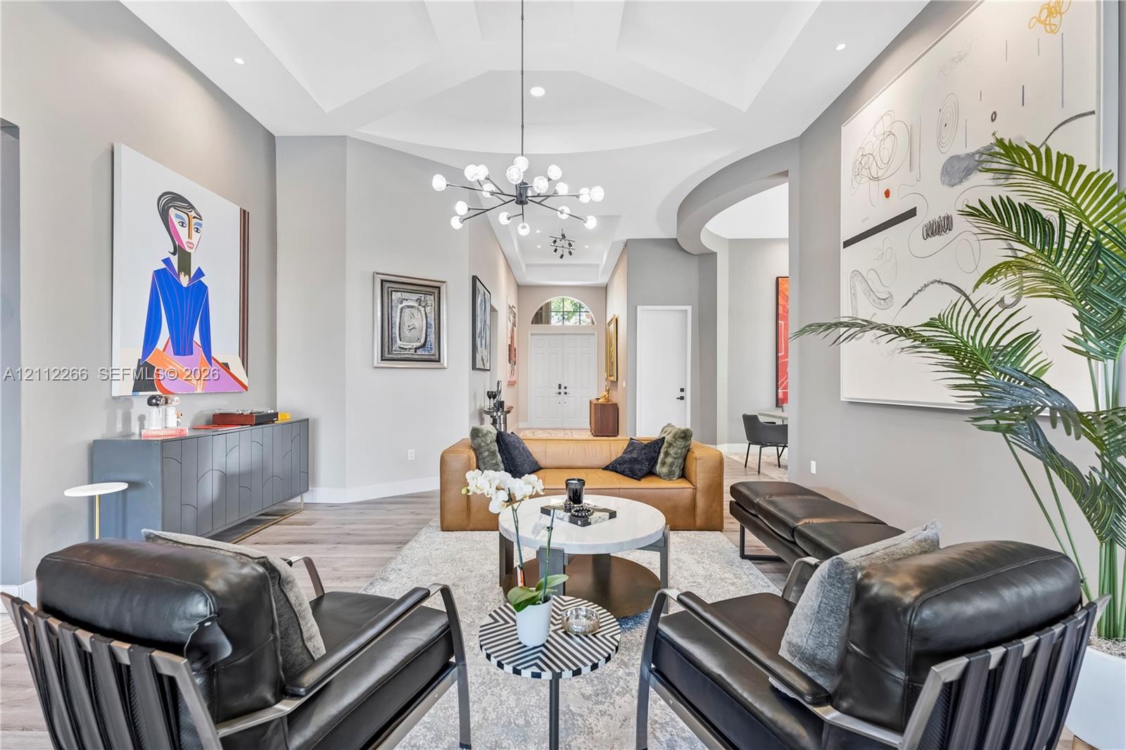 Tray ceiling with recessed lighting, multi-arm chandelier, and wood-finish flooring