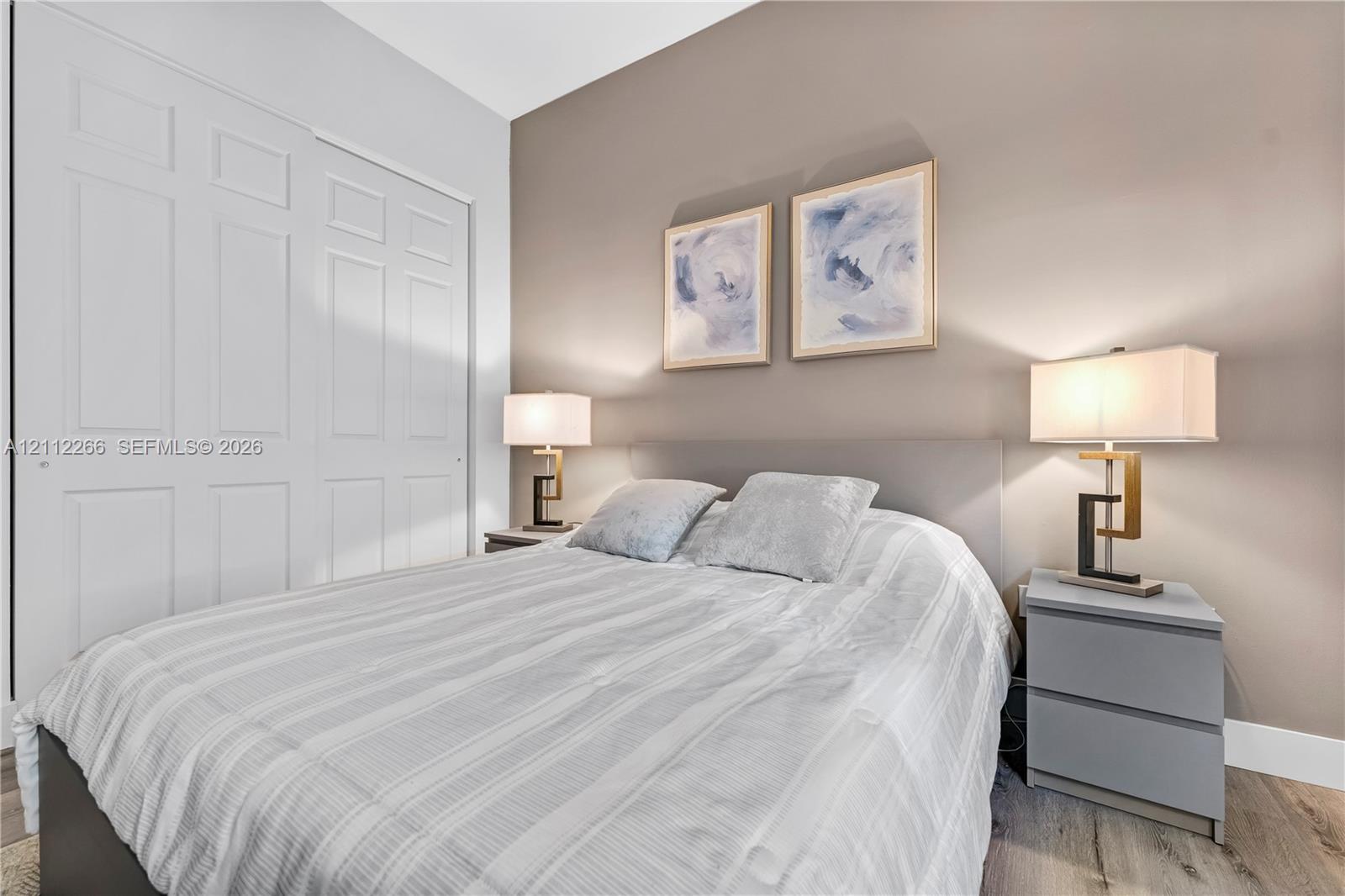 Neutral-toned room featuring wood-finish flooring, a bi-fold closet, and a painted accent wall