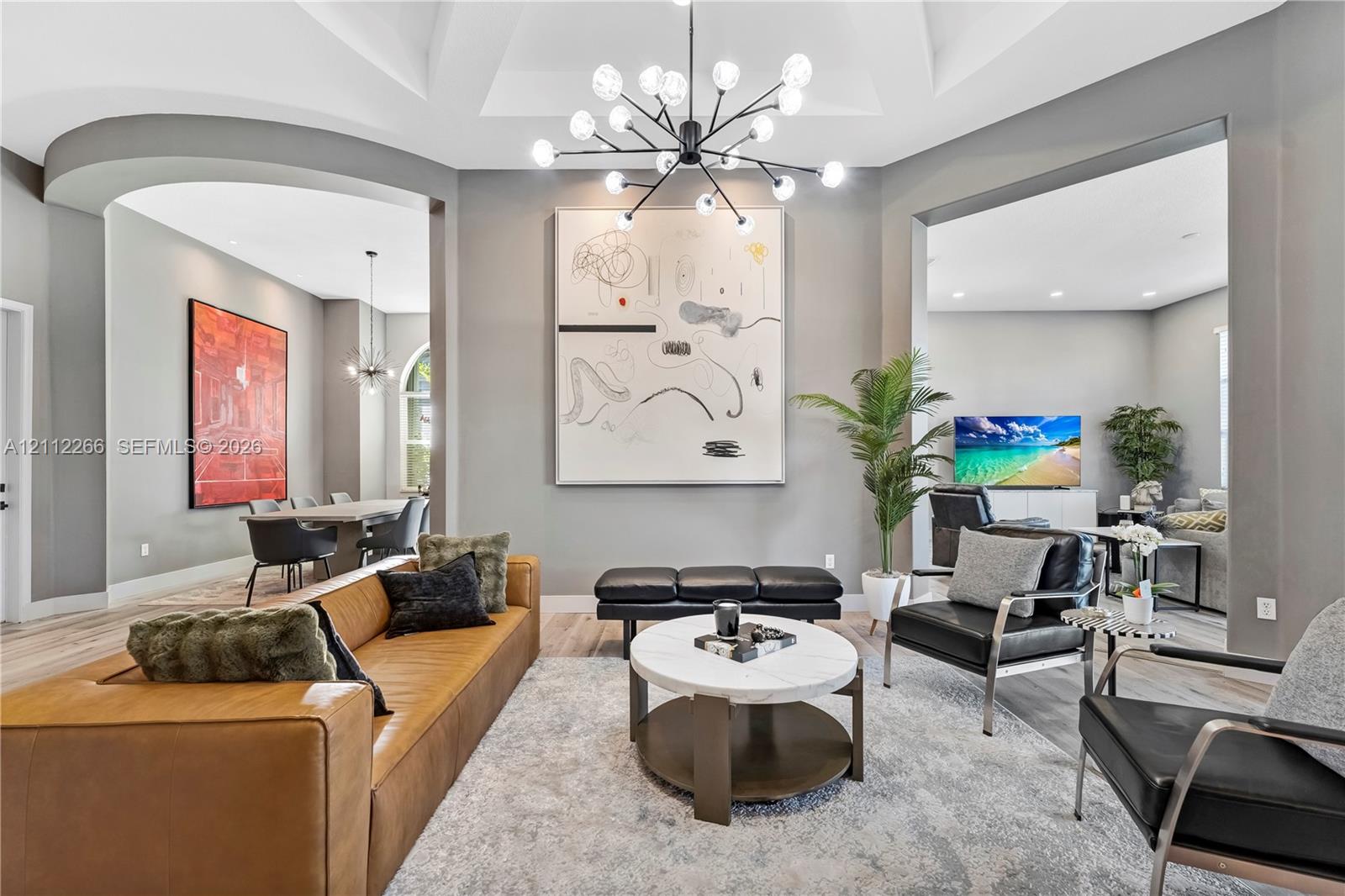 Vaulted ceilings, contemporary multi-arm chandelier, wood-finish flooring, and arched architectural openings