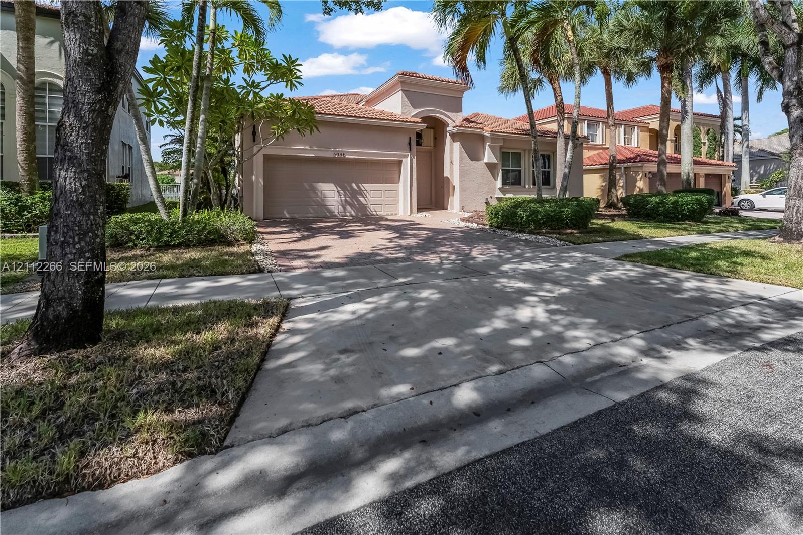 Stucco exterior featuring a clay tile roof, arched entryway, paved driveway, and attached two-car garage Stucco exterior featuring a clay tile roof, arched entryway, paved driveway, and attached two-car garage
