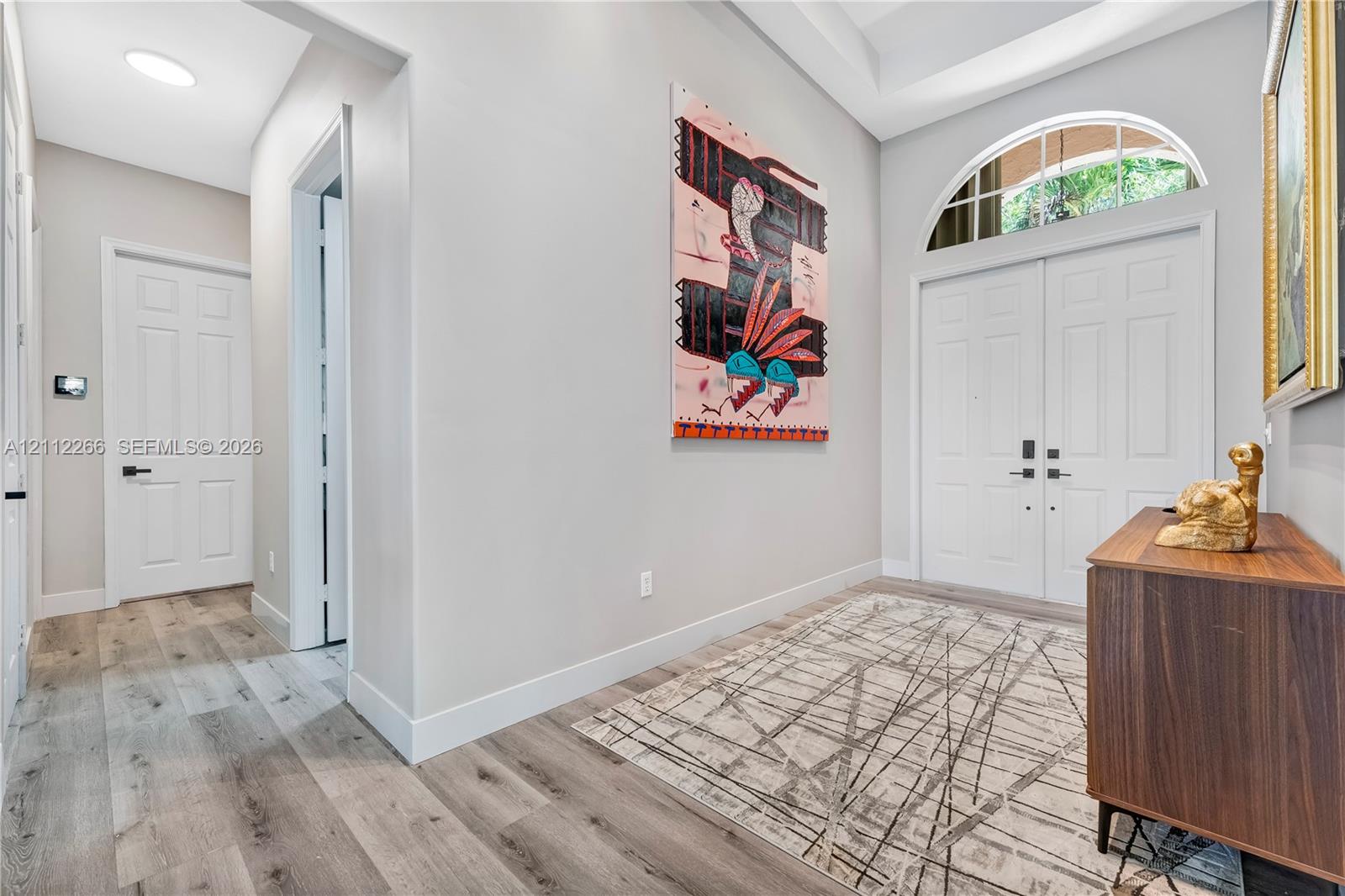 Foyer featuring double-door entry with arched transom window, high ceilings, and wood-finish flooring Foyer featuring double-door entry with arched transom window, high ceilings, and wood-finish flooring