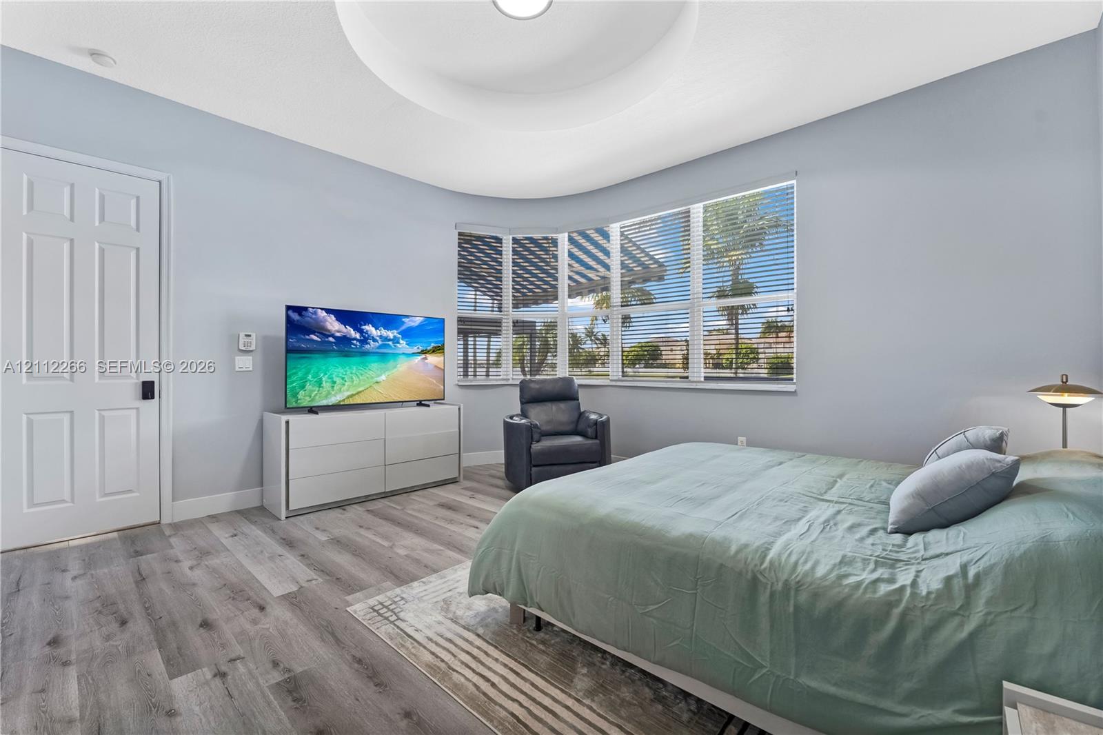Tray ceiling featuring a recessed circular design, wood-finish flooring, and expansive bay windows