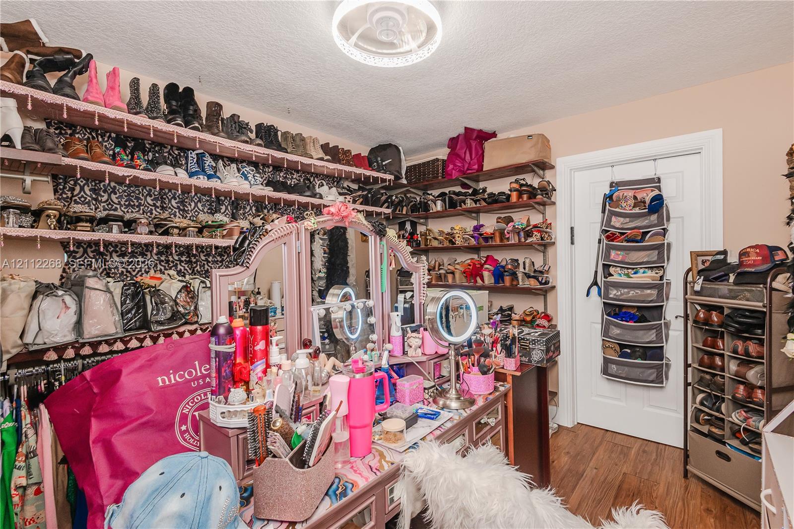 Walk-in closet featuring extensive wall-mounted shelving and wood-finish flooring