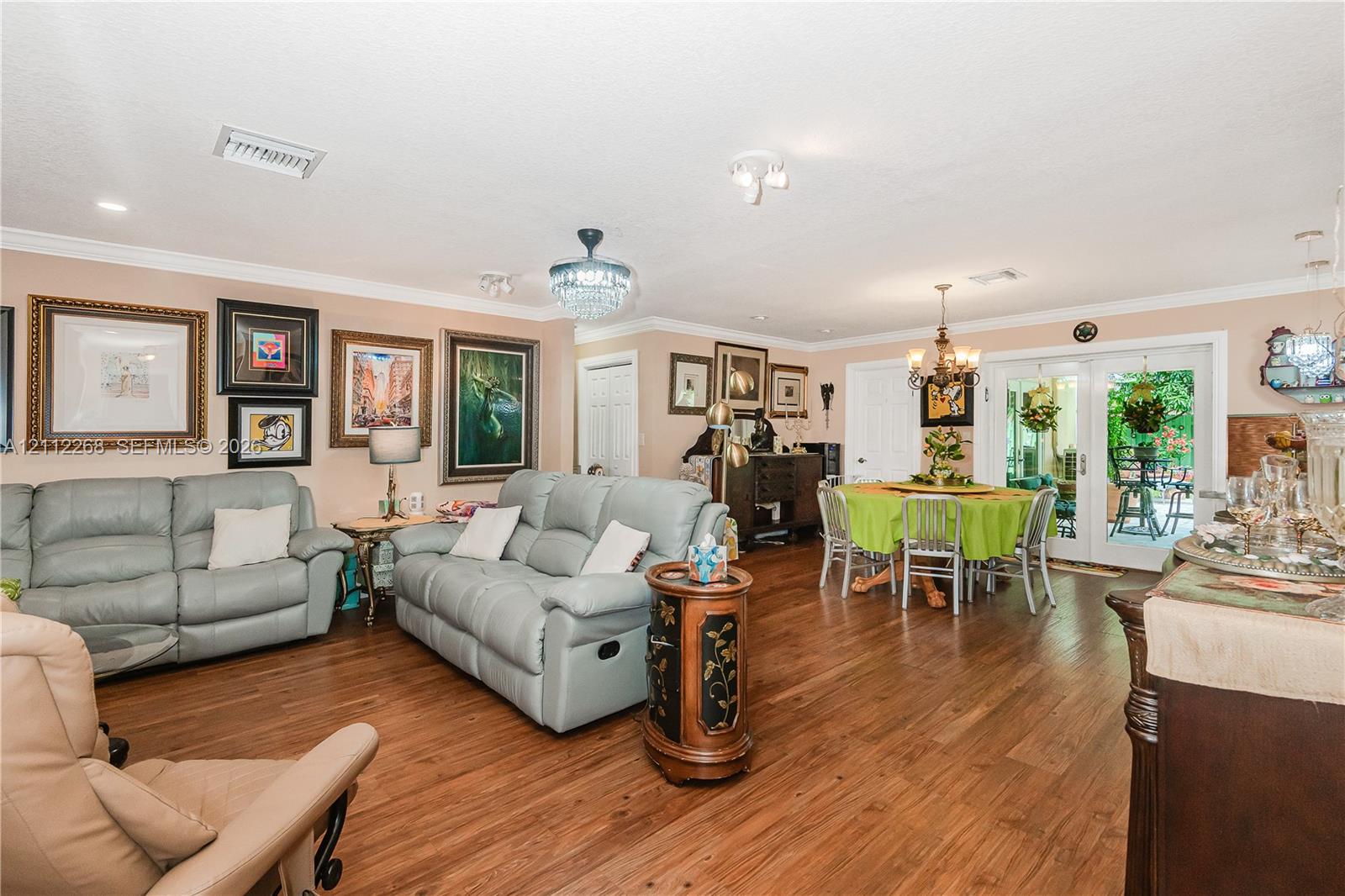Wood-finish flooring, crown molding, multi-pane glass double doors, crystal-style chandelier, and recessed lighting