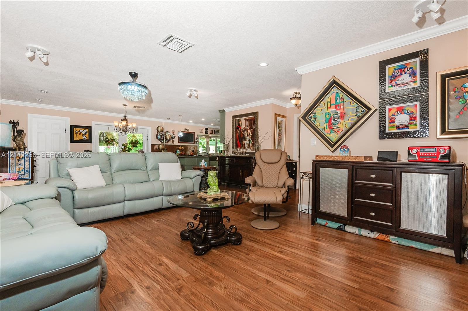 Living area featuring wood-finish flooring, crown molding, tiered crystal chandelier, recessed lighting, and double-door entryway