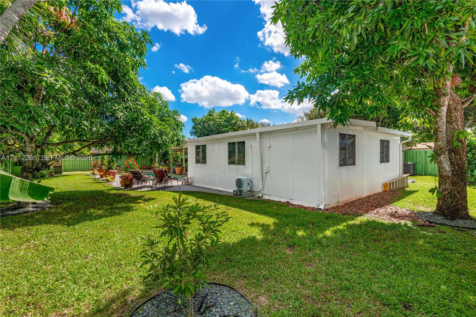 Expansive backyard featuring a lush lawn, mature shade trees, and a perimeter privacy fence
