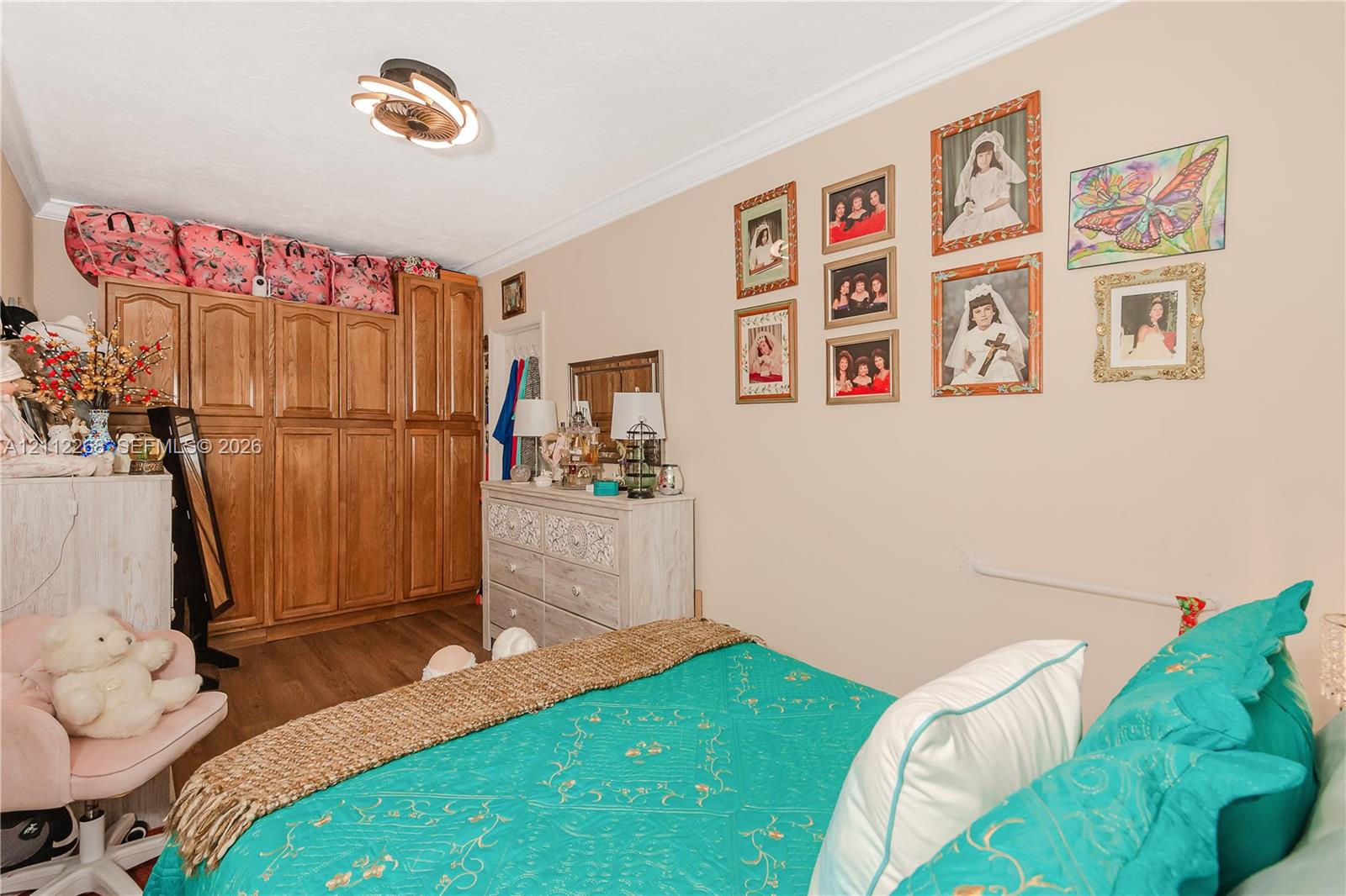 Built-in wood cabinetry, wood-finish flooring, crown molding, and contemporary flush-mount ceiling fixture
