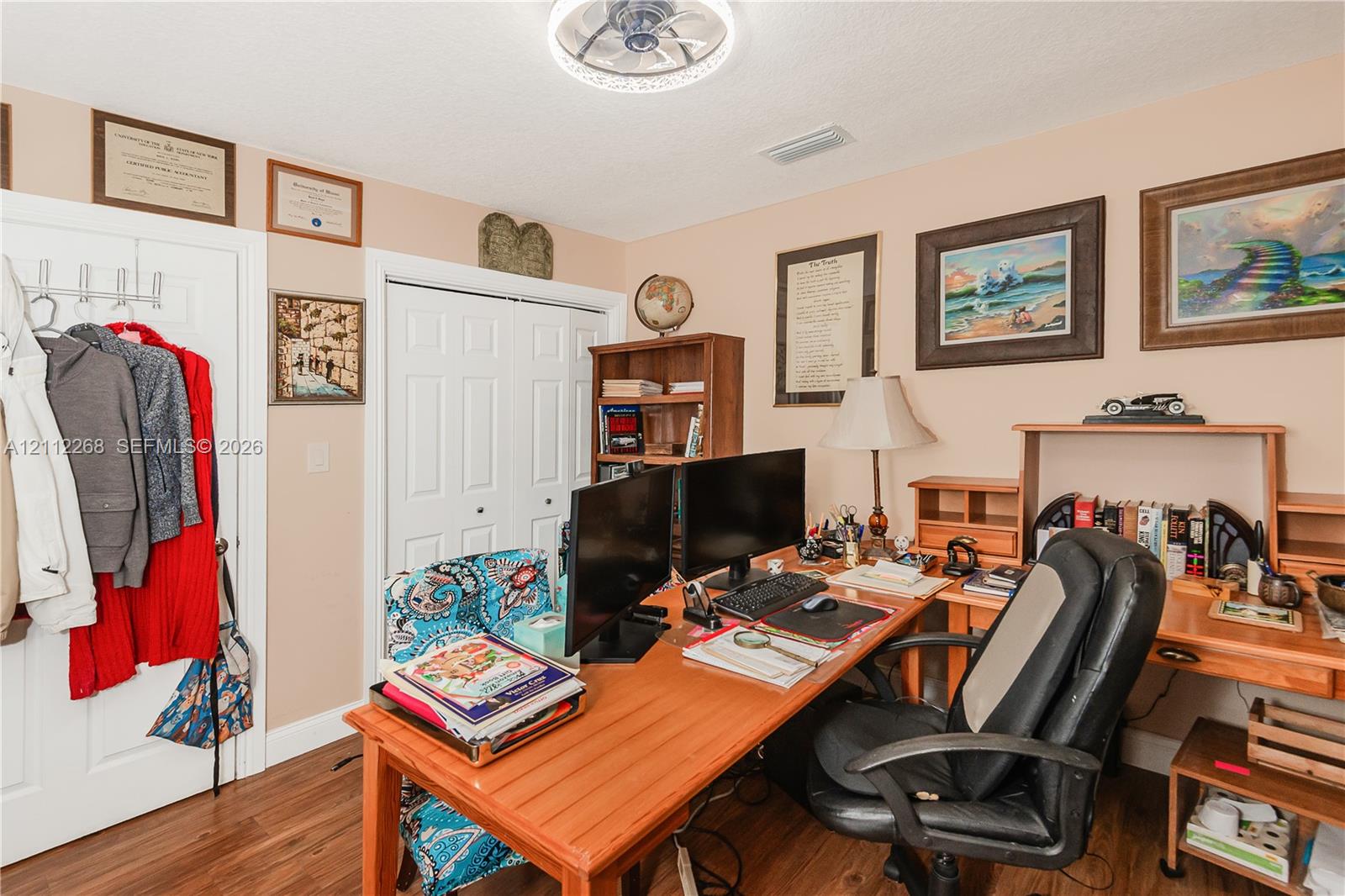 Room featuring wood-finish flooring, dual-panel closet doors, and a flush-mount ceiling light fixture