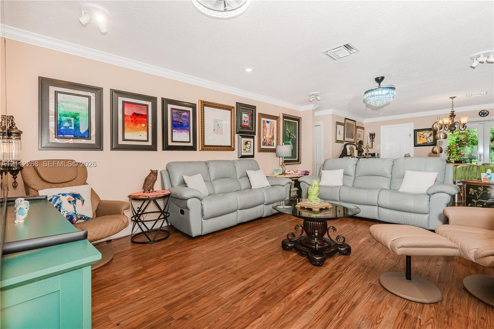 Wood-finish flooring, crown molding, and decorative ceiling-mounted light fixtures