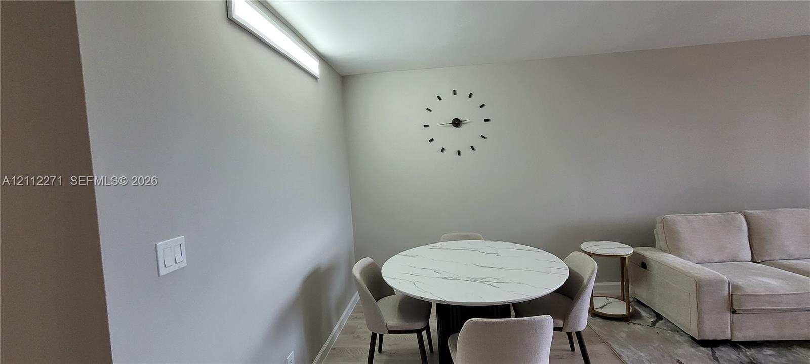 Neutral-toned walls paired with linear overhead LED lighting and wood-finish flooring