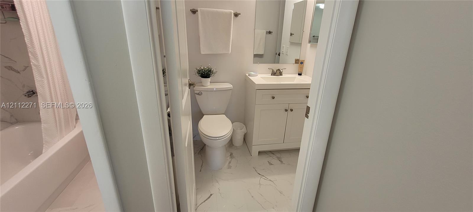 Bathroom featuring a vanity with shaker-style cabinetry, white integrated countertop, and wall-mounted mirror