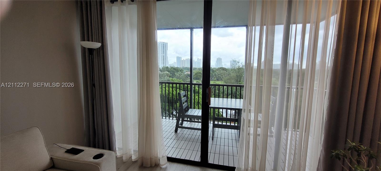 Full-height sliding glass doors opening to a covered balcony featuring slat flooring and a black metal railing
