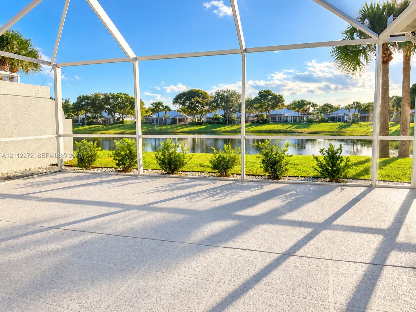 Screened-in patio with concrete flooring, water frontage, and manicured landscaping