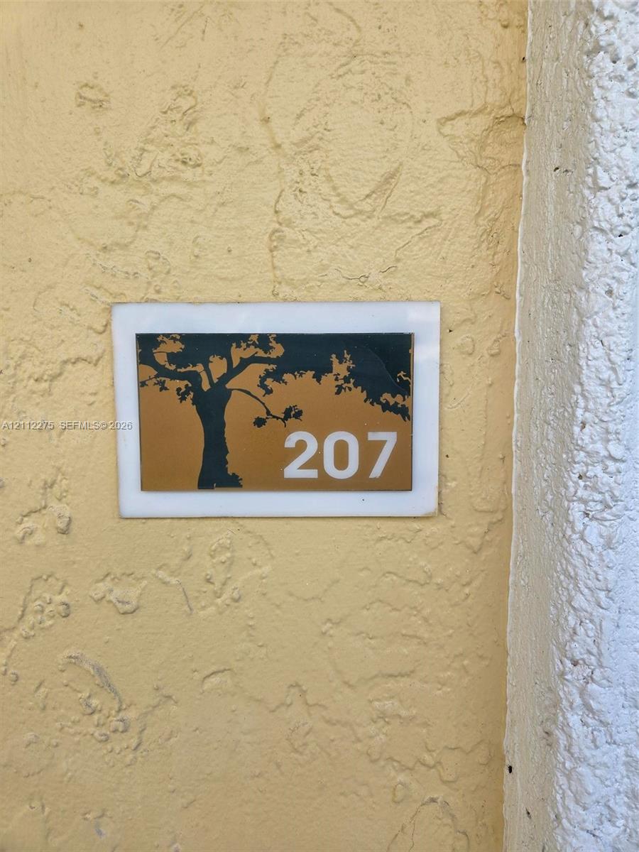 Custom wall-mounted address plaque featuring a tree silhouette graphic and numeric identification on a textured stucco exterior wall