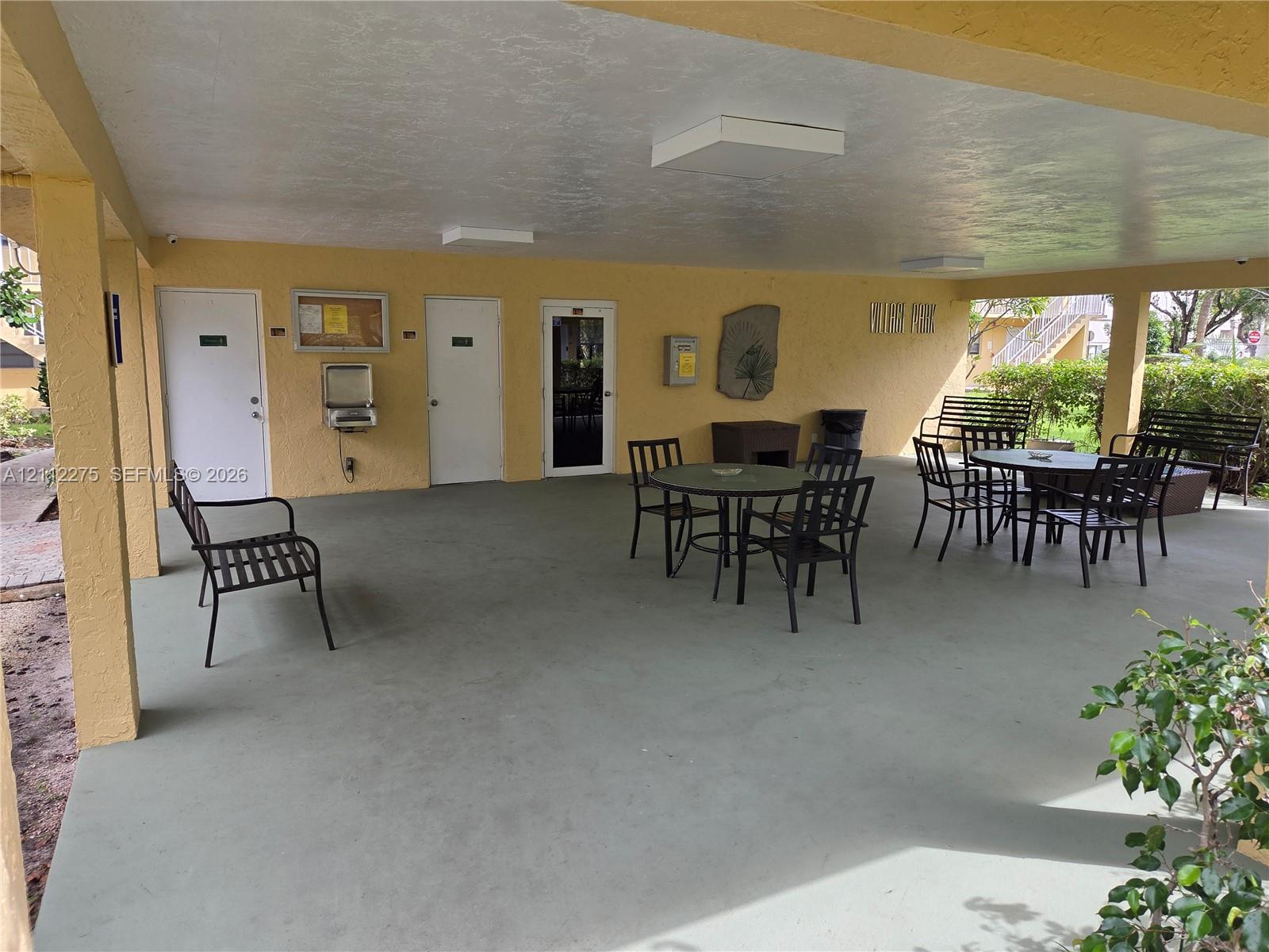 Covered outdoor pavilion featuring painted concrete flooring, recessed lighting, and multiple access doors
