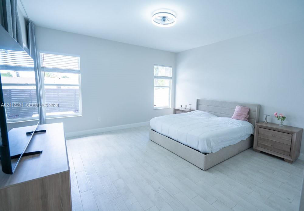 Neutral-toned interior featuring wood-finish tile flooring, recessed window frames, and a contemporary flush-mount ceiling light fixture
