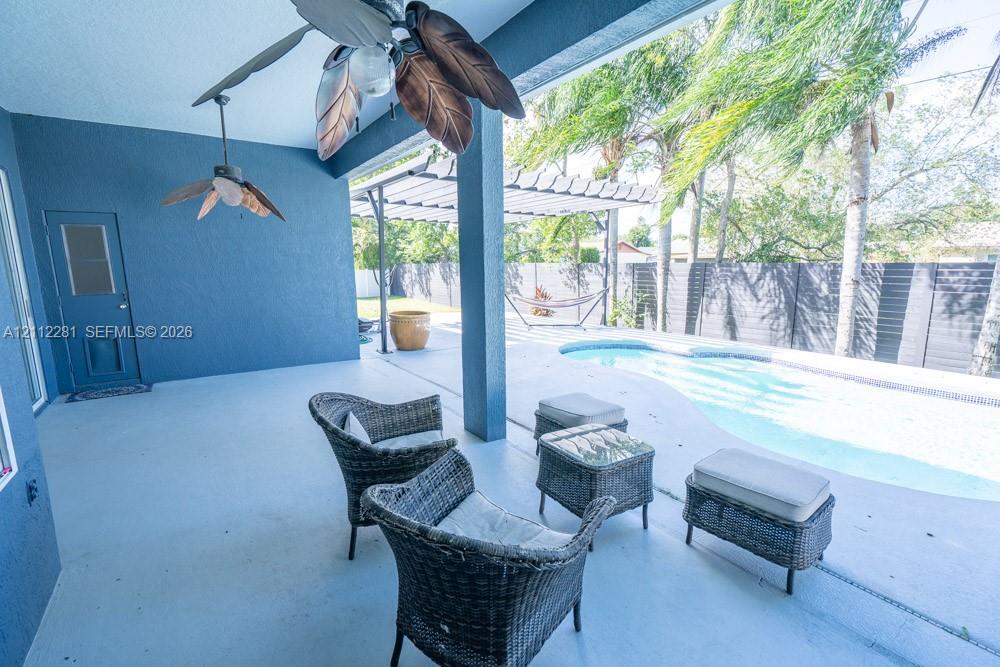Covered patio featuring two ceiling fans, in-ground swimming pool, horizontal slat privacy fencing, and a pergola-covered patio area