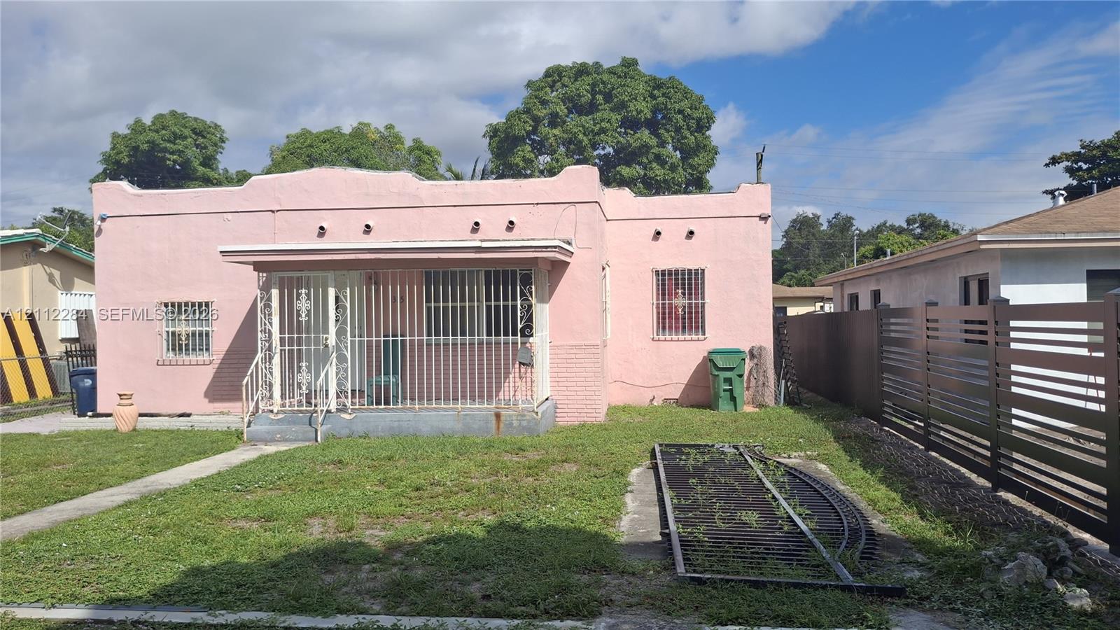 Single-story residence featuring a parapet roofline, stucco exterior, covered front porch, and metal security bars on windows and entryway