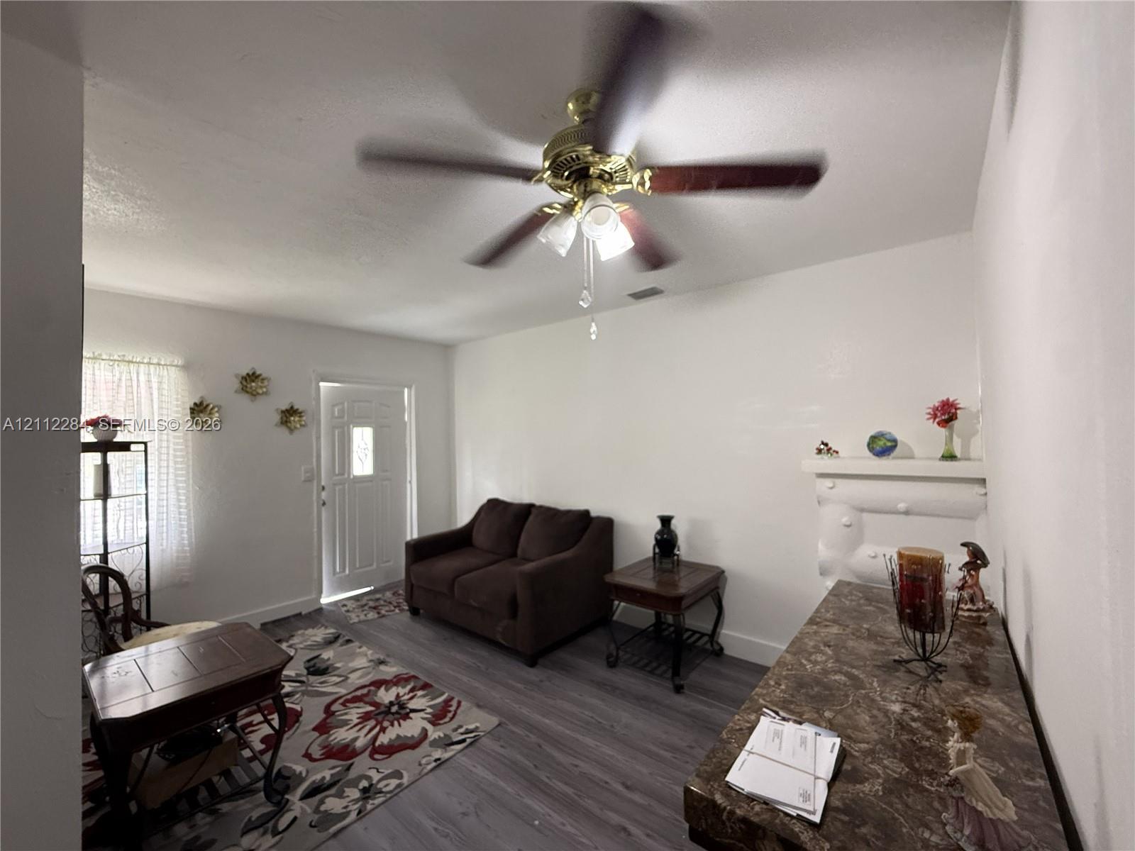 Wood-finish flooring, ceiling fan with integrated light fixture, built-in decorative wall mantle, and multi-pane entry door