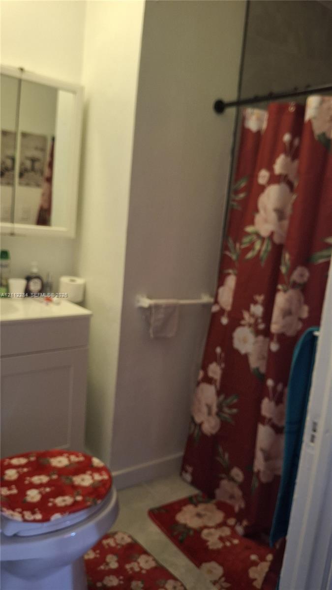 Bathroom featuring a white vanity cabinet, mirrored medicine cabinet, wall-mounted towel bar, and a shower area with a curtain rod