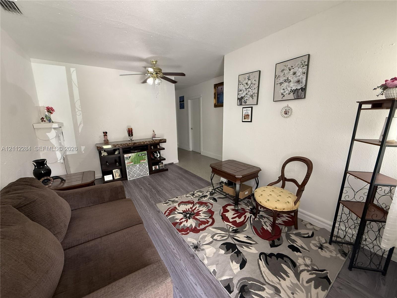 Interior space featuring neutral wall tones, wood-finish flooring, and a ceiling fan with integrated light fixture