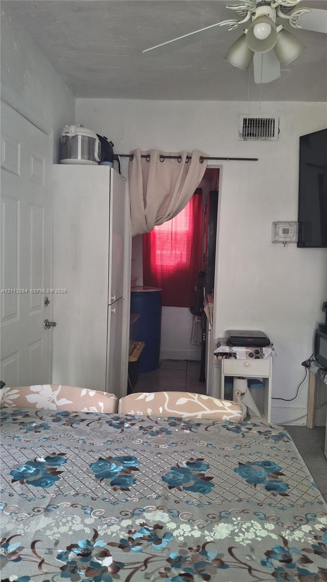 Room featuring a white paneled door, a tall built-in cabinet, and a multi-light ceiling fan