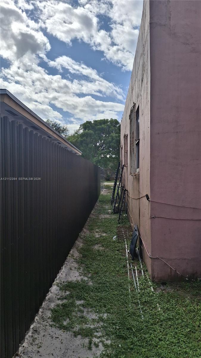 Side yard exterior featuring a vertical metal privacy fence and smooth stucco wall finish