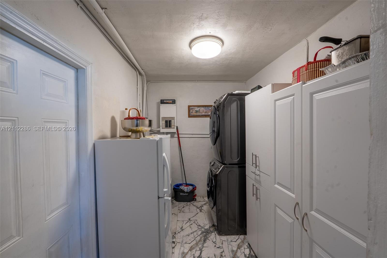Utility space featuring white shaker-style cabinetry, a dome ceiling light fixture, and patterned tile flooring