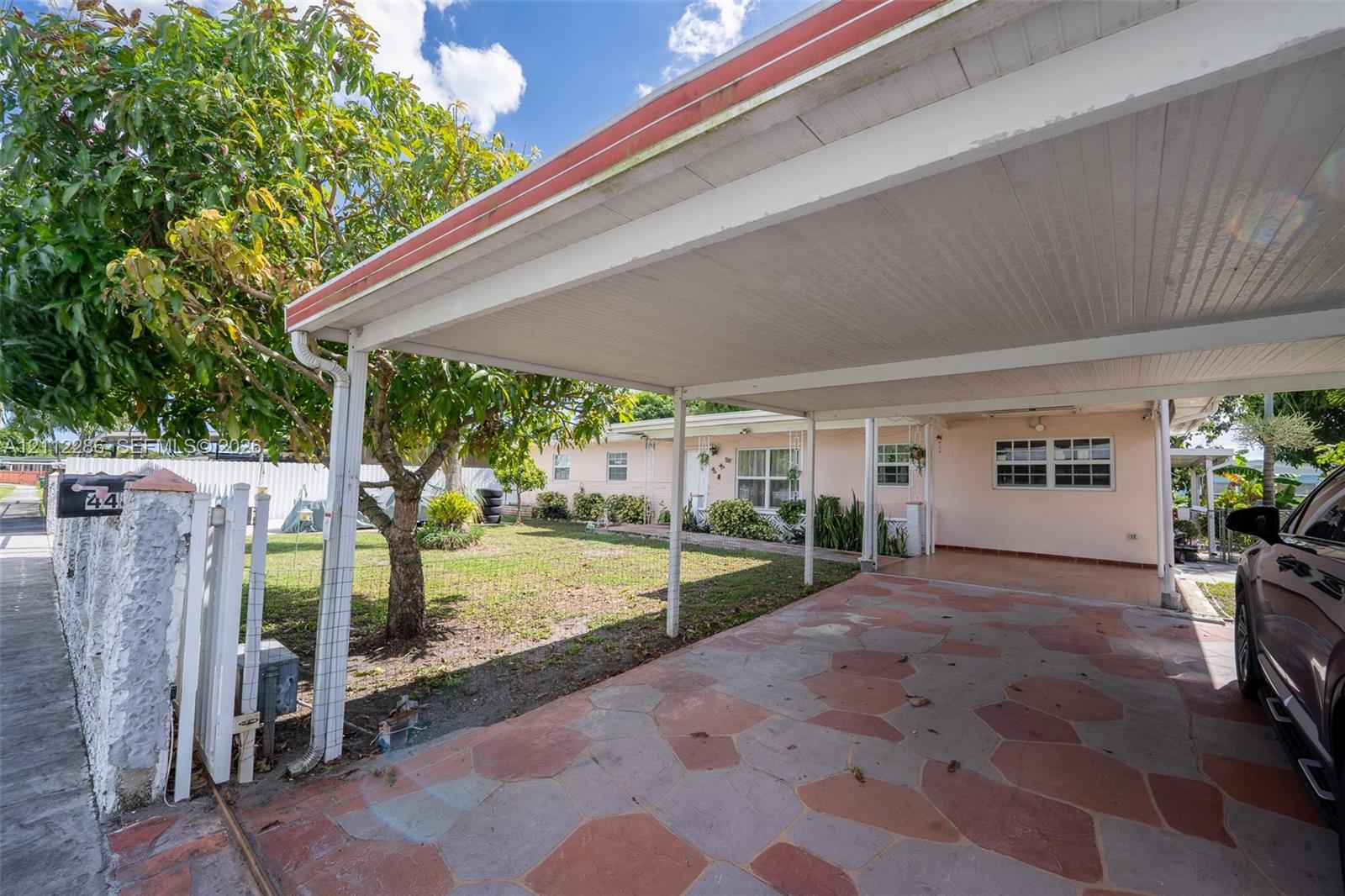 Covered carport featuring flagstone paving, integrated outdoor lighting, and a mature tree-lined front yard Covered carport featuring flagstone paving, integrated outdoor lighting, and a mature tree-lined front yard