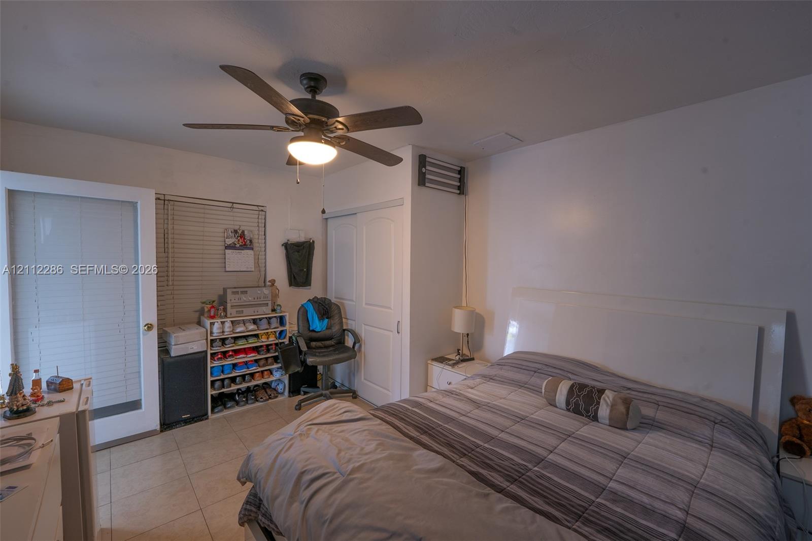 Ceramic tile flooring, ceiling fan with integrated light fixture, dual-panel closet doors, and glass-paneled exterior door