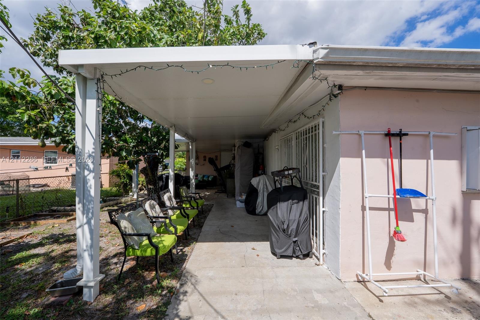 Covered exterior patio featuring a concrete floor, support pillars, and metal security bars over the exterior door Covered exterior patio featuring a concrete floor, support pillars, and metal security bars over the exterior door