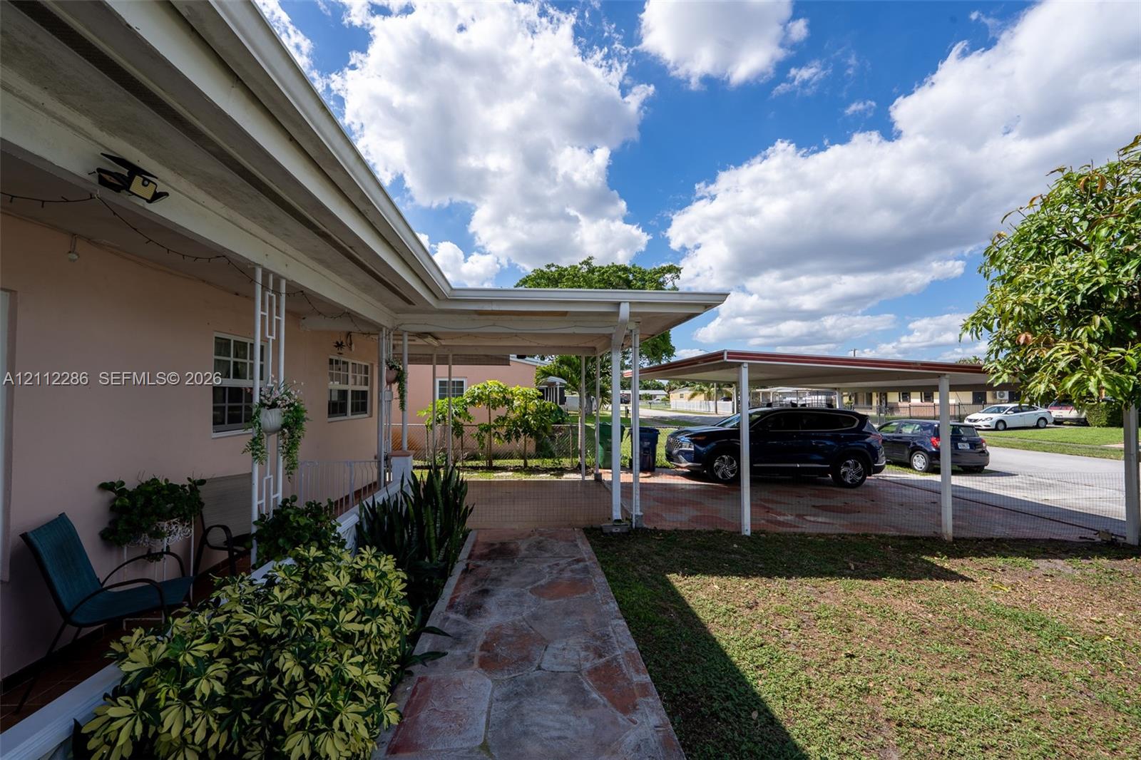 Covered entryway featuring decorative structural columns, stone-paver walkway, and attached carport Covered entryway featuring decorative structural columns, stone-paver walkway, and attached carport