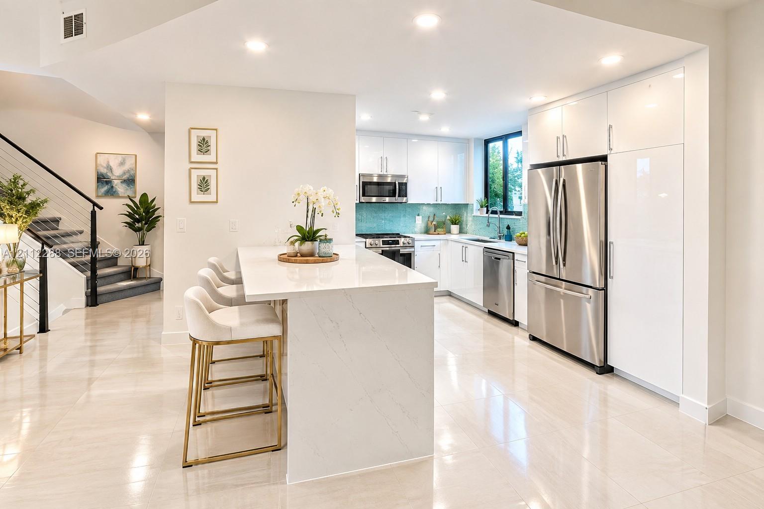 Kitchen featuring flat-panel white cabinetry, stone-finish countertops, stainless steel appliances, a center island with counter seating, and recessed lighting