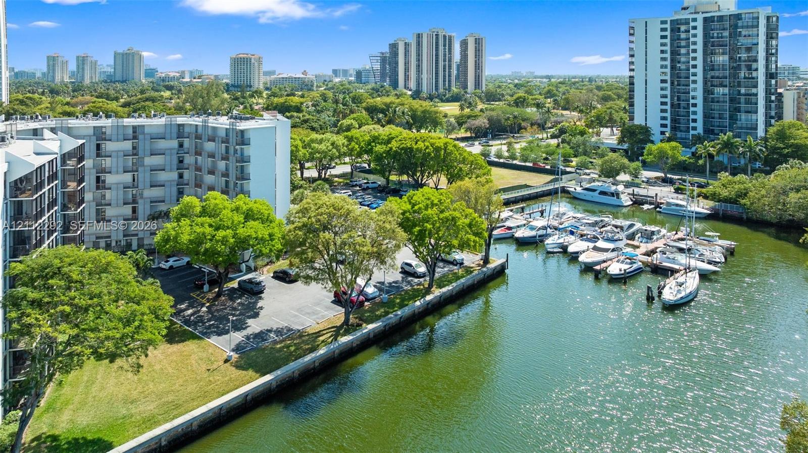 Aerial perspective of multi-story residential building featuring on-site parking, mature landscaping, paved bulkhead, and integrated boat slips Aerial perspective of multi-story residential building featuring on-site parking, mature landscaping, paved bulkhead, and integrated boat slips