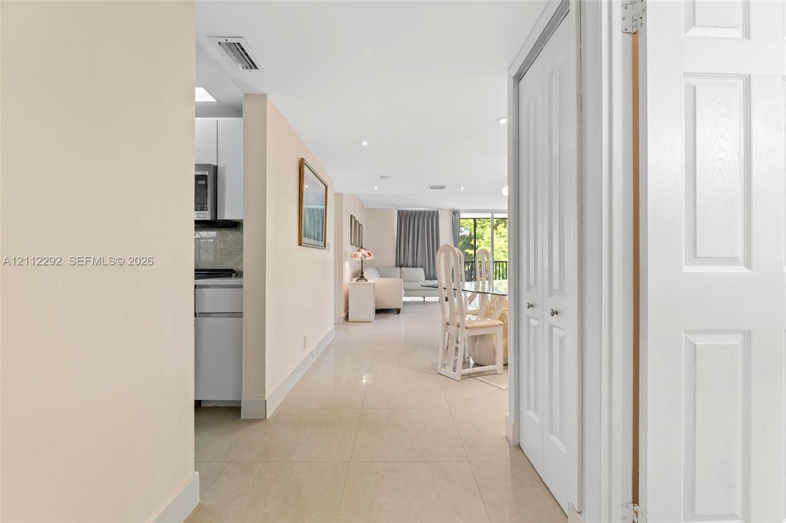 Neutral-tone tile flooring, recessed ceiling lighting, and white six-panel interior doors