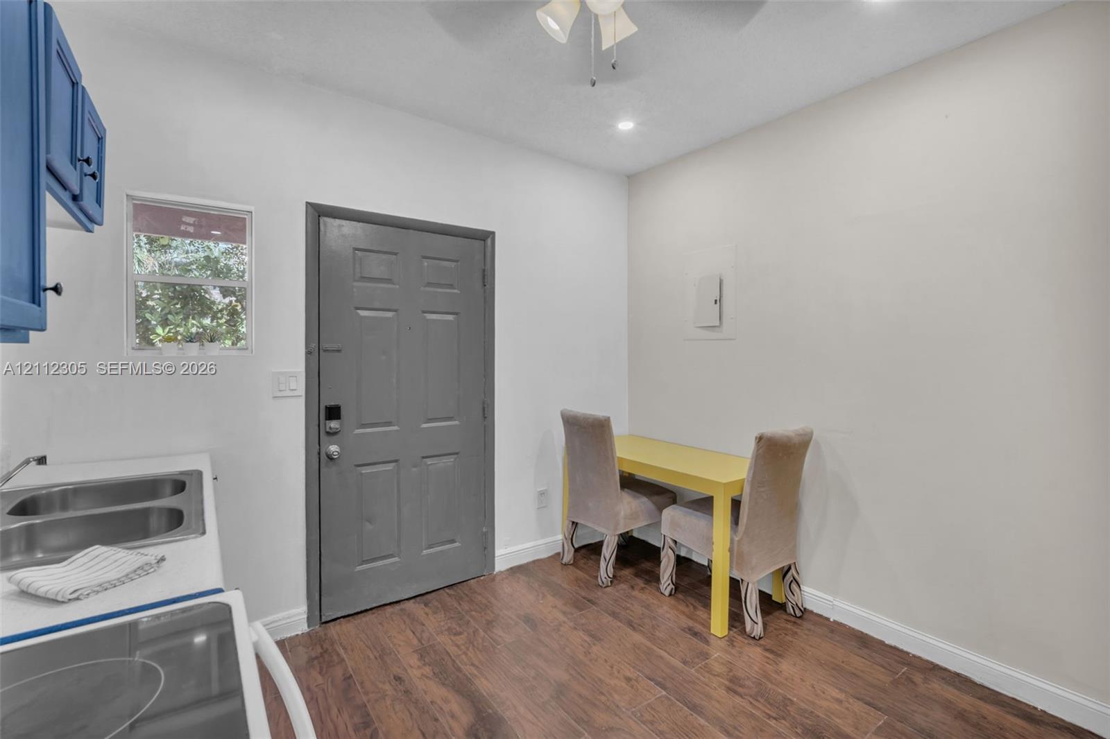 Interior space featuring wood-finish flooring, a double-basin stainless steel sink, solid-core entry door, and ceiling-mounted lighting