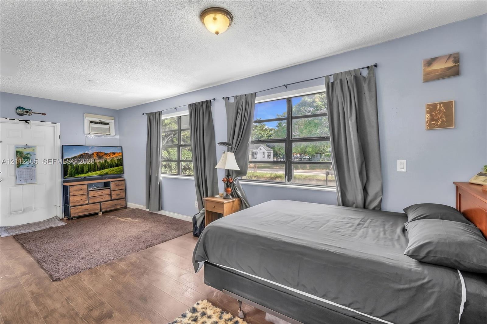 Room featuring wood-finish flooring, two large multi-pane windows, and a flush-mount ceiling light fixture