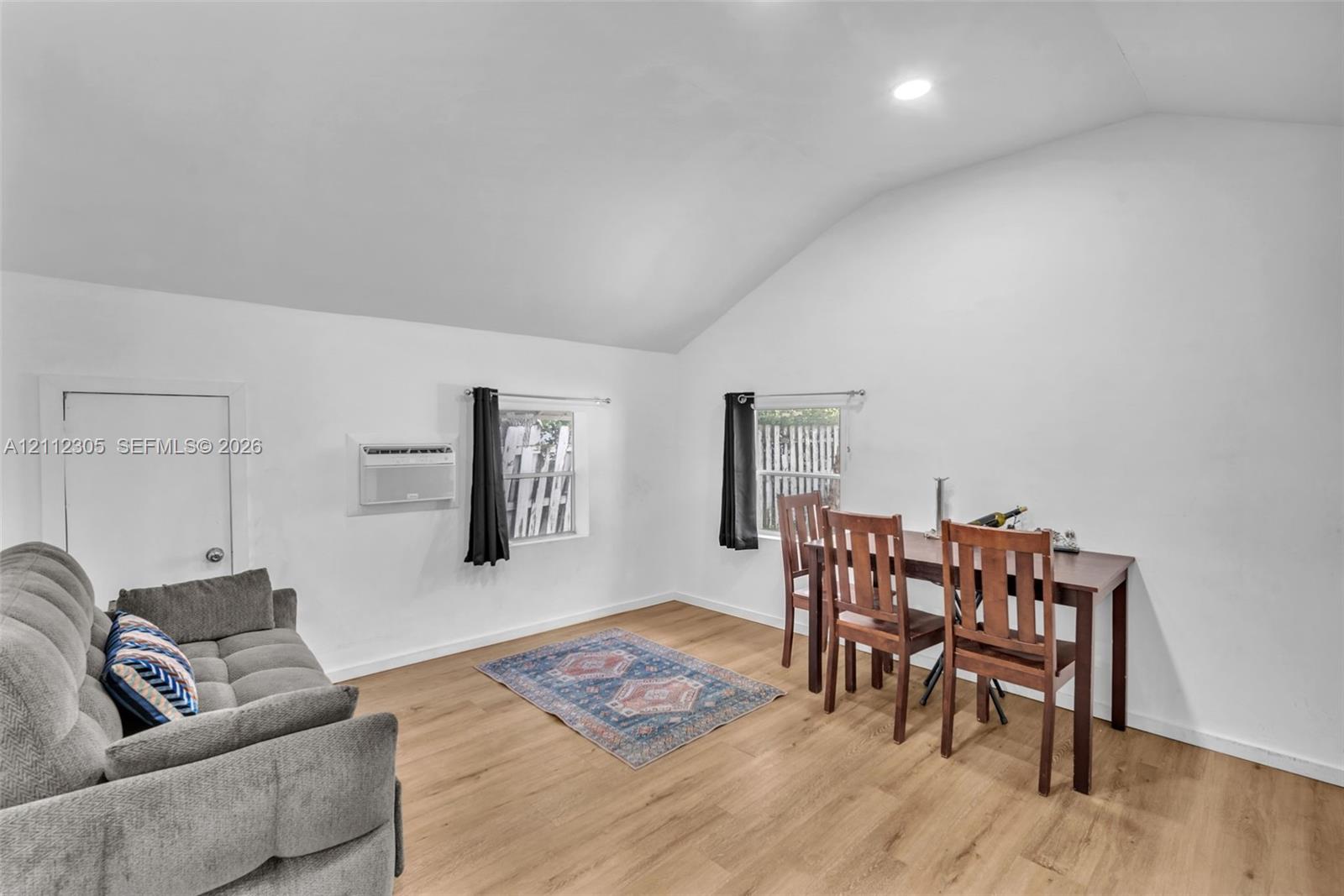 Vaulted ceiling, wood-finish flooring, recessed lighting, and wall-mounted air conditioning unit