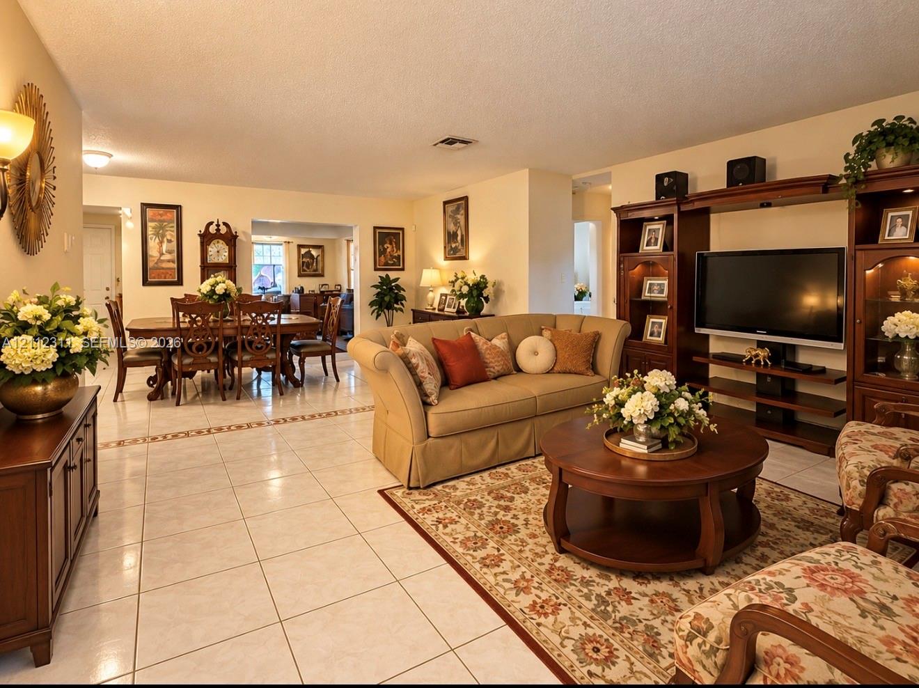 Open-concept living space featuring large-format ceramic tile flooring, built-in wooden shelving unit, and decorative tile inlay detail