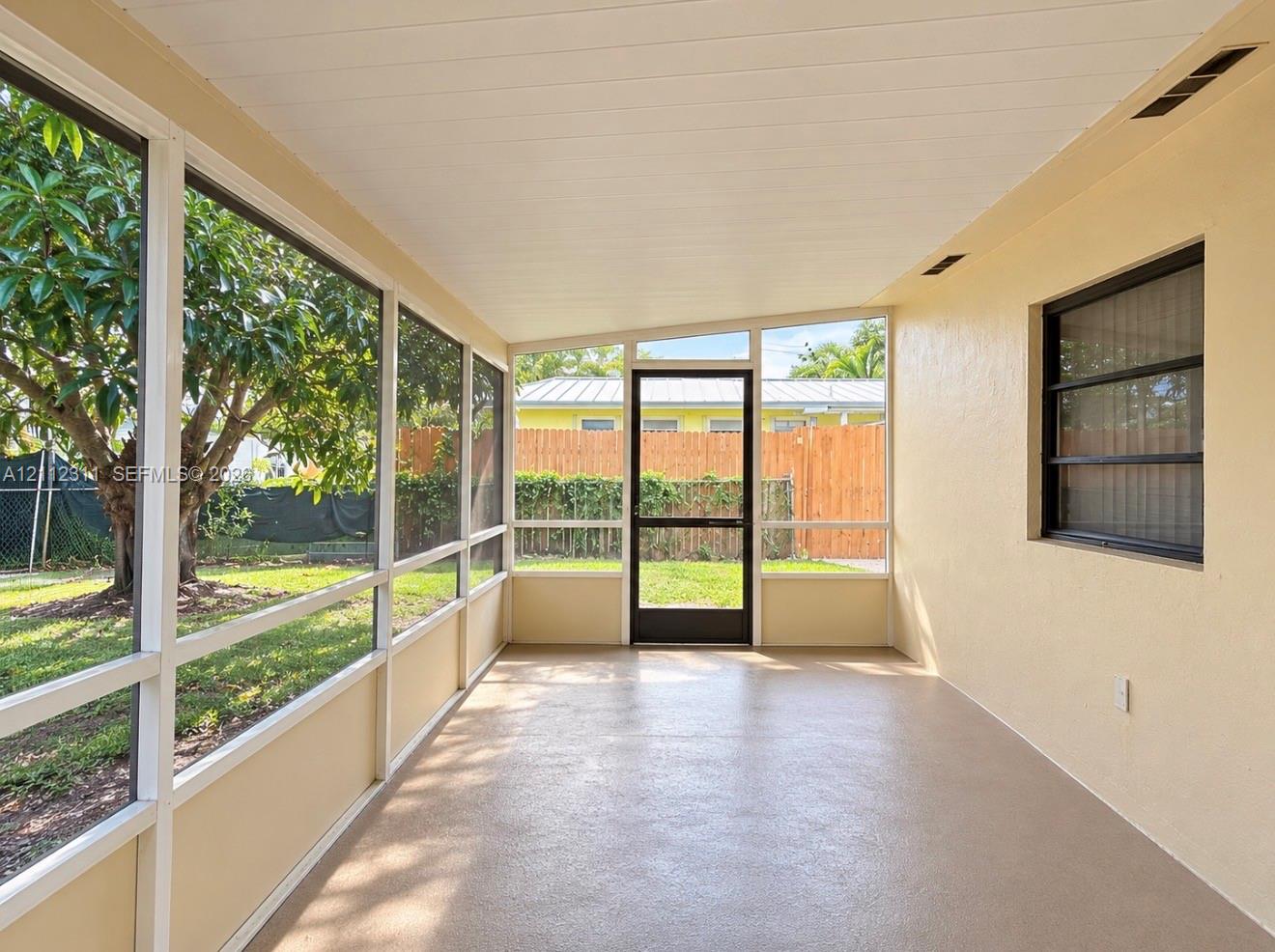 Screened-in porch featuring a textured concrete floor, paneled ceiling, and full-height window screening