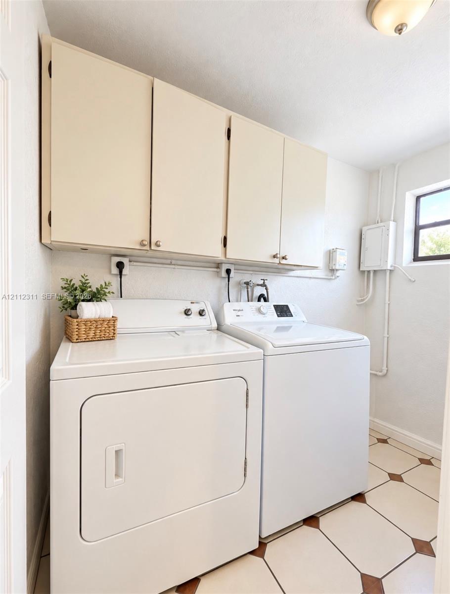 Utility room featuring white flat-panel upper cabinetry, tile flooring with diamond accents, and a fixed window