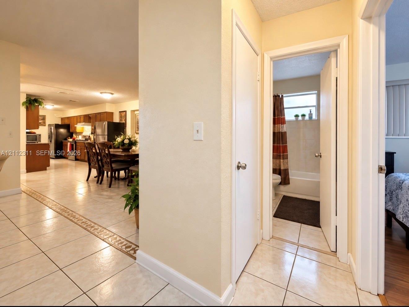 Ceramic tile flooring with decorative inlay, flush-mount lighting, and neutral wall tones