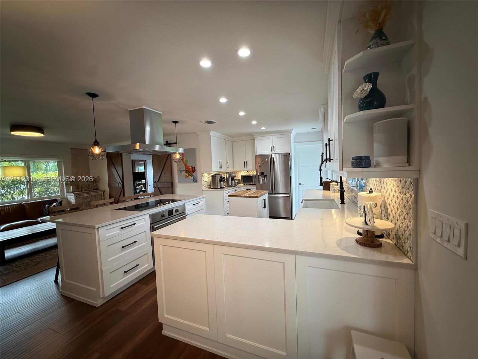 Kitchen featuring white cabinetry, quartz countertops, stainless steel appliances, a center island with a built-in cooktop and overhead range hood, and wood-finish flooring