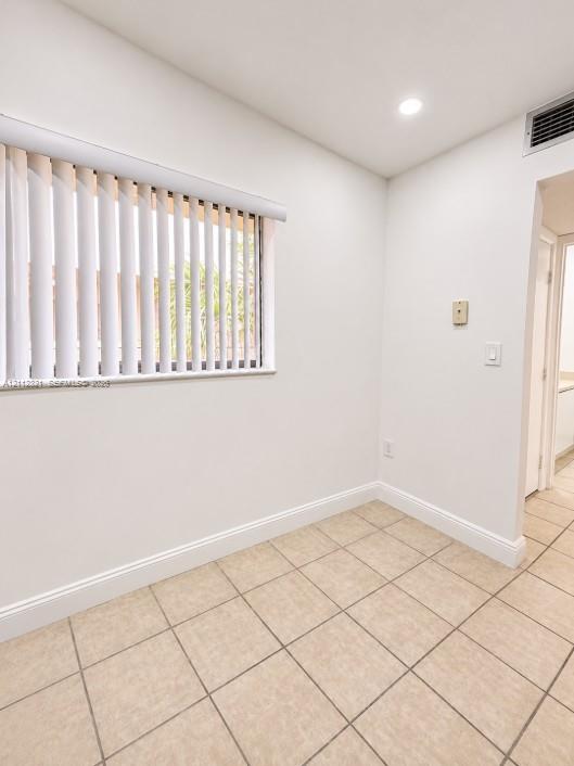 Neutral-toned ceramic tile flooring, recessed ceiling lighting, and vertical window blinds