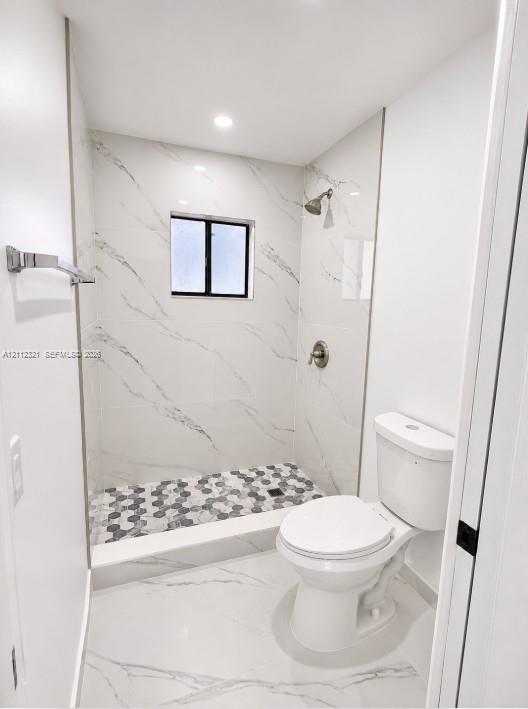 Full-height shower surround featuring large-format veined tile, contrasting hexagonal floor tile, brushed nickel fixture, and recessed lighting