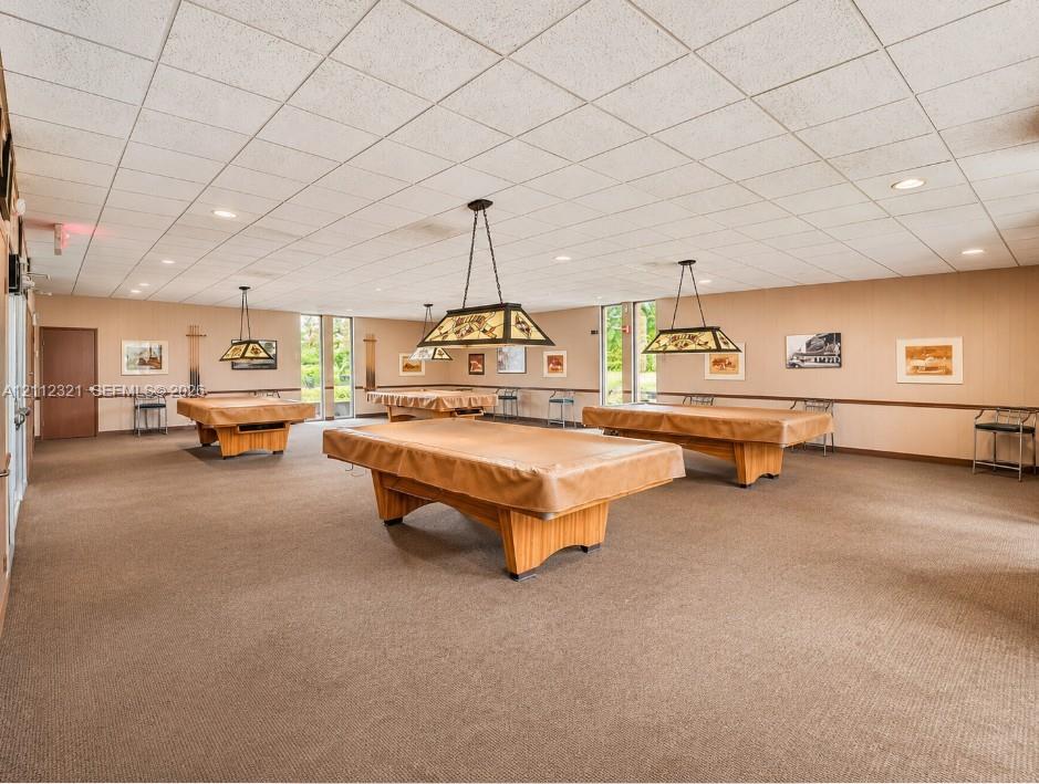 Spacious recreation area featuring a drop ceiling, wall-to-wall carpeting, recessed lighting, and built-in drop-pendant lighting fixtures